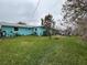 View of the large, grassy backyard showing the home's exterior and some additional storage buildings at 744 Baywood Ln, South Daytona, FL 32119