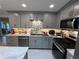 Kitchen boasts stainless steel appliances, stone backsplash, and gray cabinetry at 744 Baywood Ln, South Daytona, FL 32119