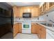 Kitchen features light wood cabinets, white appliances, and laminate floor at 100 E Kentucky Ave # K106, Deland, FL 32724