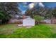 White shed in a grassy backyard with a wooden fence at 1036 Tompkins Dr, Port Orange, FL 32129