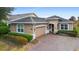 Tan single-story house with a paved driveway and lush landscaping at 1105 Gardenshire Ln, Deland, FL 32724