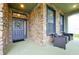 Covered front porch with stone exterior and wicker chairs at 1106 Woods Landing Dr, Minneola, FL 34715