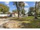 Spacious backyard featuring mature trees, lush lawn, and partially fenced perimeter at 1240 W Voorhis Ave, Deland, FL 32720