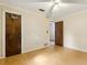 Sun-filled bedroom features hardwood floors, a ceiling fan, and two dark wooden doors at 1240 W Voorhis Ave, Deland, FL 32720