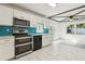 Open kitchen design with white cabinets, stainless steel appliances, and bright turquoise backsplash at 1240 W Voorhis Ave, Deland, FL 32720