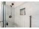 Close-up of shower with white marble-style tile, built-in niche, shower head, and grab bar at 1401 S Palmetto Ave # 614, Daytona Beach, FL 32114