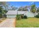 Light teal house with a gray roof, driveway, and lush green lawn at 1412 Oak Forest Dr, Ormond Beach, FL 32174