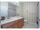 Clean bathroom with single vanity, shower/tub combo, and striped wallpaper at 204 Wellington Woods Ave, Deland, FL 32724
