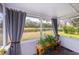 Relaxing screened porch overlooking a pond, featuring gray curtains and potted plants at 2758 Turnbull Cove Dr, New Smyrna Beach, FL 32168