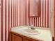 Clean bathroom with a pedestal sink and red and white striped wallpaper at 347 Castlewood Ln, New Smyrna Beach, FL 32168