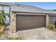 Attached garage with brown door and stone accents at 347 Castlewood Ln, New Smyrna Beach, FL 32168