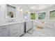 Bathroom featuring dual vanities with marble countertops, a soaking tub, and decorative wallpaper at 396 Muddy Creek Ln, Ormond Beach, FL 32174