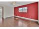 Empty bedroom with light hardwood floors, a window, and a vibrant red accent wall at 641 Hartley Ave, Deltona, FL 32725