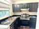 Kitchen featuring stainless steel appliances, black cabinets, and granite countertops at 236 Plaza Oval, Casselberry, FL 32707