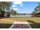 Scenic view of the lake from the backyard featuring a stone paver patio and lush greenery at 2424 India Blvd, Deltona, FL 32738
