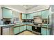 Kitchen with light green cabinets and stainless steel appliances at 2625 Sweet Springs St, Deltona, FL 32738