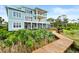 Three-story light teal home with a boardwalk leading to a backyard patio at 2806 Bay Vista Ct, New Smyrna Beach, FL 32168