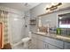 Tastefully renovated bathroom with tiled shower, granite-topped vanity, and framed mirror at 30215 Tavares Ridge Blvd # 11, Tavares, FL 32778