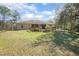 View of the backyard with a deck, green grass, and mature landscaping at 43747 Choctaw St, Deland, FL 32720