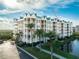 Stunning waterfront condo building featuring manicured grounds, tropical landscaping, and a bright coastal design at 4672 Riverwalk Village # 8406, Ponce Inlet, FL 32127