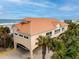 Coastal building exterior with covered parking, a metal roof, and lush palm trees at 4672 Riverwalk Village # 8406, Ponce Inlet, FL 32127