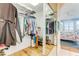 Organized walk-in closet with hanging clothes, shelving, and drawers, leading to a bedroom with coastal decor at 4672 Riverwalk Village # 8406, Ponce Inlet, FL 32127