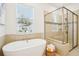 Bright bathroom features a soaking tub, large window, and frameless glass shower for a luxurious spa experience at 475 W Main St, Lake Helen, FL 32744