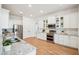 Bright kitchen features white cabinetry, granite countertops, stainless steel appliances, and wood-look floors at 475 W Main St, Lake Helen, FL 32744