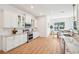 Open kitchen featuring white cabinetry, stone countertops, stainless steel appliances, tile backsplash, and wood-look floors at 475 W Main St, Lake Helen, FL 32744
