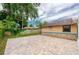 An expansive beige brick patio surrounds a home with stone accents, perfect for outdoor entertaining at 949 Tall Pine Dr, Port Orange, FL 32127