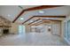 Open-concept living room featuring a stone fireplace, vaulted ceilings with wood beams, and sliding glass doors at 949 Tall Pine Dr, Port Orange, FL 32127