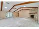 Spacious living room featuring a stone fireplace, vaulted ceilings with wood beams and a glass door that leads to the lanai at 949 Tall Pine Dr, Port Orange, FL 32127