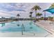 A large community pool with clear water, surrounded by palm trees, sunshades, and lounge chairs at 105 Cerise Ct, Daytona Beach, FL 32124
