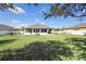 Large fenced-in backyard featuring a spacious lawn, covered porch, and a brick fire pit at 108 Blanco Dr, Deland, FL 32724