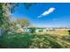 Green backyard with a fire pit, trees, and a turquoise home with a blue sky overhead at 1120 Mistletoe Dr, Daytona Beach, FL 32117