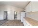 Open kitchen features white cabinets, appliances and tile floors, leading to bathroom and living areas at 1195 10Th St, Daytona Beach, FL 32117