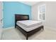 Bedroom with wood bed frame, mattress and neutral walls with teal accent wall at 1372 Lombardi Ct, Poinciana, FL 34759