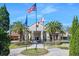 Inviting clubhouse entrance with American and state flags, palm trees, and a well-manicured brick walkway at 1372 Lombardi Ct, Poinciana, FL 34759
