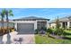Charming single-story home featuring a gray exterior, a two-car garage, screened in front porch, and well-manicured landscaping at 1372 Lombardi Ct, Poinciana, FL 34759