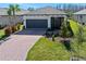 Charming one-story home with a manicured lawn, brick driveway, gray garage door, and fresh landscaping at 1372 Lombardi Ct, Poinciana, FL 34759