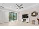 Bright living room featuring tile floors, a modern ceiling fan, a large flat-screen TV and sliding glass doors at 1372 Lombardi Ct, Poinciana, FL 34759