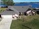 Aerial view of a well-maintained brick home featuring a spacious lawn, two-car garage, and serene lake views at 2075 Little Farms Ct, Deltona, FL 32738