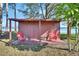 Wooden shed with red chairs offers a cozy outdoor space for relaxation, surrounded by lush greenery and water views at 2075 Little Farms Ct, Deltona, FL 32738