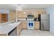Well-lit kitchen with stainless steel appliances, light wood cabinets, and tile flooring at 2610 Hialeah Ave, The Villages, FL 32162
