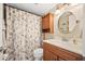 Cozy bathroom featuring a wood cabinet, round mirror, and decorative shower curtain at 2711 N Halifax Ave # 184, Daytona Beach, FL 32118
