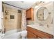 Cozy bathroom featuring a wood cabinet, round mirror, and tiled shower with shelving at 2711 N Halifax Ave # 184, Daytona Beach, FL 32118