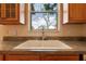 Close up of kitchen sink under window with brown countertop and cabinets, with a view to outside at 3633 Sickle St, Orlando, FL 32812