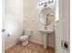 Cozy powder room with pedestal sink, mirror, toilet, decorative lighting, and neutral walls at 3633 Sickle St, Orlando, FL 32812