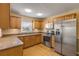 Modern kitchen with stainless steel appliances, wood cabinetry, tile backsplash, and eat-in potential at 564 Cambridge Cir, South Daytona, FL 32119