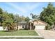 Charming single-story home with a two-car garage, beautiful landscaping, and mature palm trees under a sunny sky at 583 Wilburton Dr, Deltona, FL 32738